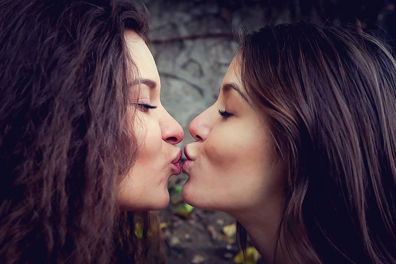 two attractive women kissing each other on the lips